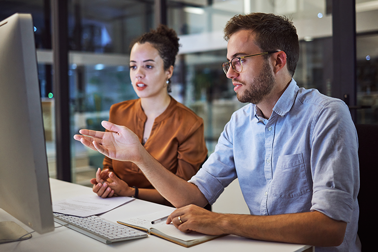 Ein Mann und eine Frau sitzen in einem Büro vor einem Computer