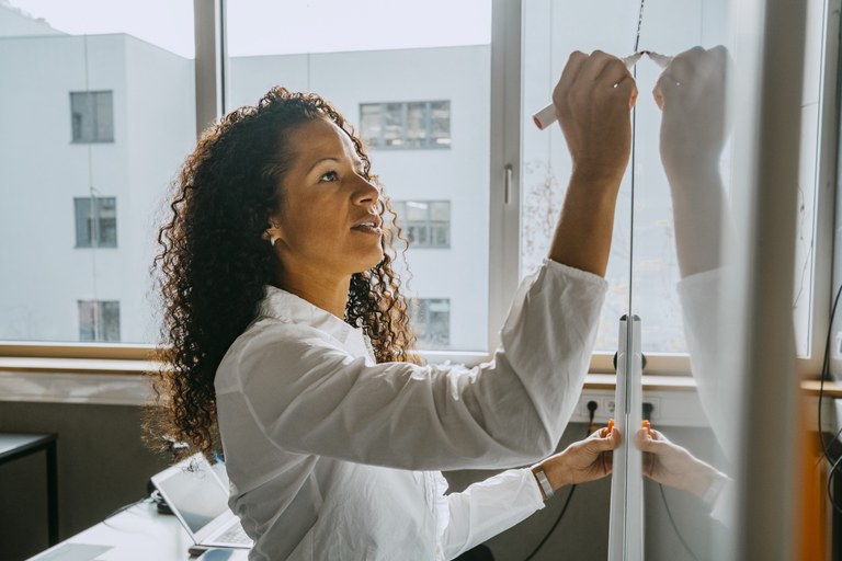 Junge Dozentin schreibt an ein Whiteboard